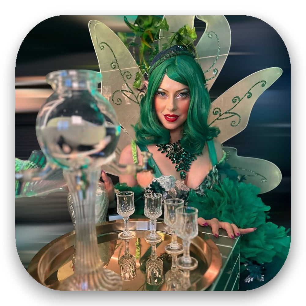 Die Absinth Fairy in Smaragdgrün mit funkelnden Flügeln – Magie pur vom GLITTERIMPERIUM von Elli Fatle. Jetzt verzaubernde Walking Acts für dein Event buchen!